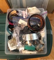 Plastic bin filled with assorted women's belts in various colors and materials, showing a top-down view of the collection packed tightly.