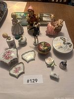 Overview photo showing all 16 porcelain figurines, decorative perfume bottles, and trinket boxes arranged on a table.