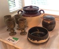 Full view of McCoy stoneware items including 4 speckled goblets, large two-tone covered pot, small lidded jar with spoon, and drip-glaze bowl on a counter near window.
