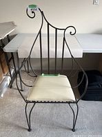 Front view of the metal entry chair showing the curved metal backrest with scroll designs and white cushion seat.