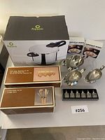 Photo showing Fresco stainless steel pressure cooker box, copper measuring spoon set, copper kitchen utensils box, four stainless steel serving dishes with handles, and two Coquilles St. Jacques food packs.