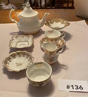 Top angle view of the lot showing the Royal Albert Val D'or 50th Anniversary tea set consisting of teapot, creamer, cup and multiple matching small dishes along with the Nippon raised bowl.