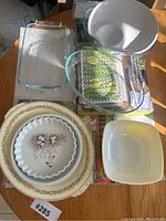Photo showing a variety of kitchenware items including Pyrex glass bakeware, ceramic serving platters and plates arranged on a table.