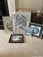 Full view of collection of framed art, showing five pieces on carpet