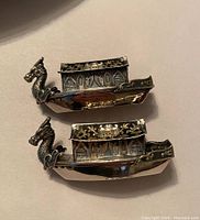 Two detailed sterling silver Japanese dragon boat salt and pepper shakers featuring dragon heads and floral cabin designs.