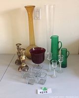 Various vintage coloured and Italian glass items including vases, pitchers, candlesticks, and glassware shown on a white surface.