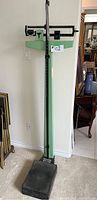 Full view of the vintage Health O Meter mechanical scale showing the green metal frame and height rod.