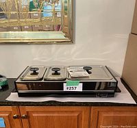West Bend Buffet Server with three lids, two Pyrex dishes inside, placed on counter with paperwork