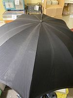 Top exterior view of a black antique umbrella showing fabric and metal ribs