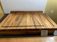Front view of rectangular wooden cutting board showing juice groove and integrated wood stand on one side.