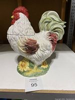 Side view of large porcelain rooster cookie jar with detailed painting and sunflower base, showing its overall shape and size.