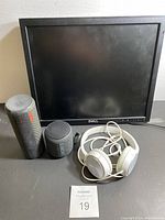 Dell monitor, UE Ultimate Ears and Sony Bluetooth speakers, white Sony wired headphones laid in front