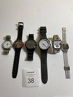 Six men's watches laid side by side showing various bands and faces