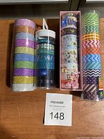 Grouped rolls of masking tape in various designs including glitter, celestial motifs, geometric patterns, floral and Asian-inspired themes.