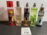 Full lot of five fragrance mist bottles lined up, showing all labels and bottle shapes.
