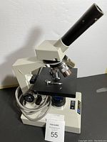 Full view of the Meiji microscope showing the eyepiece tube, revolving nosepiece with objectives, and stage with slide clips.