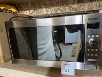 Front view of Panasonic inverter microwave oven showing the full door, stainless steel finish, and MaxSold auction tag 51.