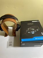 Photo showing Sennheiser Momentum headphones on wooden display stand next to original retail box.