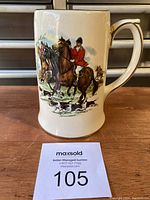 Front view of vintage ceramic beer stein showing detailed fox hunt scene with rider in red jacket on horse and hounds in foreground.