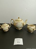 Full view of vintage Sadler tea set showing teapot, sugar bowl with lid, and creamer on black surface against plain background.