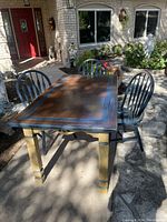 Rectangular primitive style wooden dining table with brown and blue hand painted top with four blue painted wooden chairs around it.