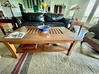 Front view of the mission style Stickley oak coffee table with grid-patterned top and lower shelf in a living room setting.