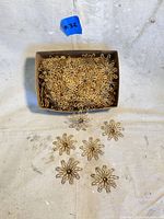 Box filled with vintage brass flower jewelry parts with some spread outside to show detail