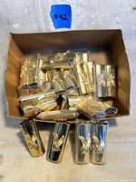 Box of 36 vintage gold-toned Bic lighter covers with embossed eagle design, some stacked and others side by side.