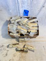 Box containing 58 vintage gold Bic lighter covers individually wrapped in clear plastic bags