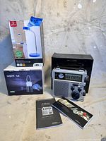 Lot contents with boxed LED desk lamp from Globe, boxed Lepro LED lantern, and unboxed L.L.Bean FR300 radio with manuals.