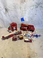 Full lot view showing all vintage diecast fire trucks, helicopters, fire alarm box, fire extinguisher, and badge.