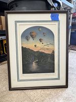 Framed and matted etching leaning against storage bins on floor