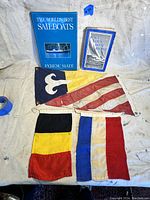 Photo showing two nautical sailing books and four vintage nautical signal flags laid out against a light background.