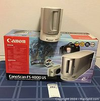 Canon CanoScan FS 4000 US scanner positioned on top of its original box featuring product graphics and branding.
