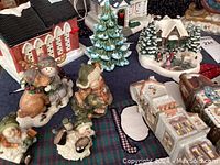 Assorted ceramic and resin Christmas village buildings and figurines depicting children with snowmen and holiday scenes