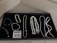 Full view of all faux pearl necklaces and bracelets laid flat in a black tray, showing size and bead variations.