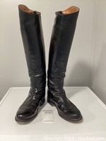 Front view of both black leather riding boots standing upright showing smooth polished exterior and round toe shape.