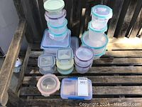 Lot of various Snapware plastic kitchen storage containers stacked together showing variety of shapes and pastel-colored snap-lock lids.