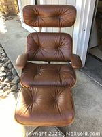 Front view of the mid-century modern brown leather lounge chair with tufted cushions and wooden armrests and backrest
