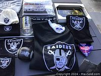 Photo of varied Oakland Raiders memorabilia including apparel, glassware, collectibles, and keychains