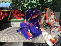 Three blankets draped over wicker patio seating showing overall patterns and colors