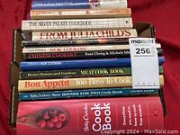 Photo of stacked vintage cookbooks in a box showing titles including Betty Crocker, Julia Child, The Silver Palate, Bon Appetit, and others.