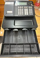 Open cash drawer with multiple compartments for bills and coins, showing the organization inside the drawer.