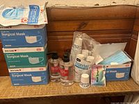 Photo showing three boxes of BYD Care surgical masks, multiple hand sanitizer bottles, stacks of disposable cups, a lanyard with pass holder, and a coffee mix sachet.