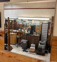 Mirror panel mounted on wall reflecting salon equipment and furniture, showing condition and presence of clips and support.