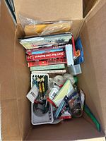 Top view of box showing mixed office supplies and business books stacked