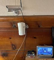Photo of two wall-mounted security cameras wired to a color LCD monitor showing live footage.