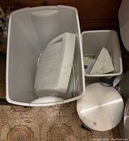 Photo showing large rectangular plastic bin with lid removed, smaller plastic bin inside, and round stainless steel pedal bin in front.