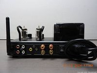 Rear view of the amplifier showing RCA inputs, speaker binding posts, headphone jack, power switch, power input, and Bluetooth antenna