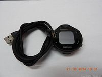 Garmin Approach G12 GPS device with USB cable laid out, front view showing screen and buttons.